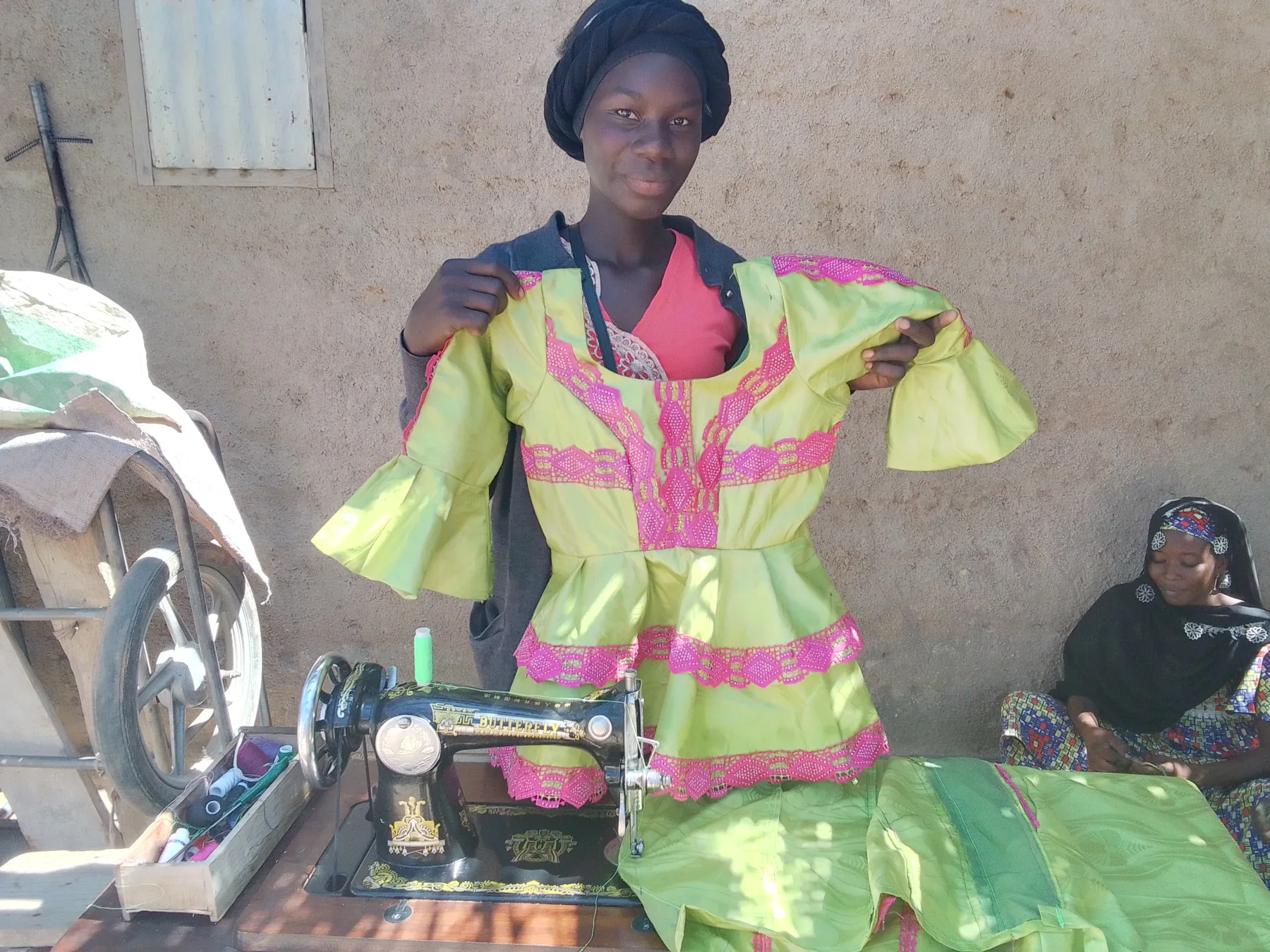 Couturière présentant une robe confectionnée dans son atelier